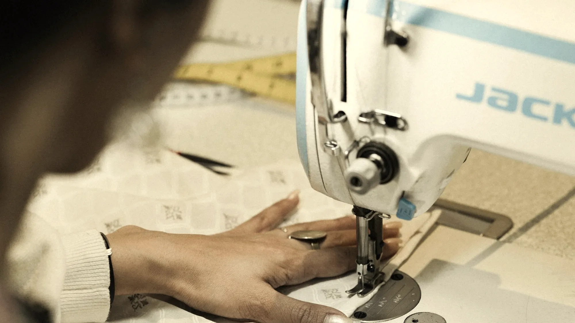 Mains guidant un tissu sous le pied-de-biche d'une machine à coudre.